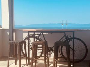a table with wine glasses and a bike on a balcony at Морска къща ЕММА in Ofrínion