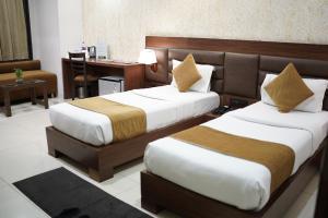 a hotel room with two beds and a desk at Hotel LA PEARL, Bhopal in Bhopal