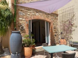 een patio met een tafel en een paarse parasol bij "MAS TRAMONTANE "chambres d'hôtes et studio avec piscine dans parc arboré in Ille-sur-Têt