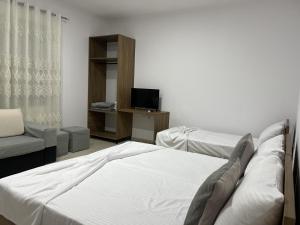 a bedroom with a bed and a couch and a television at Guesthouse Osumi in Berat