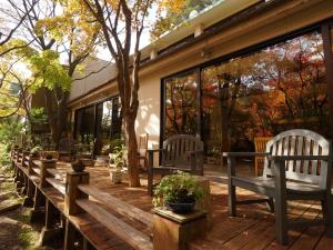 una terraza de madera con sillas y plantas. en Kirishima Momijidani Seiryuso, en Kirishima