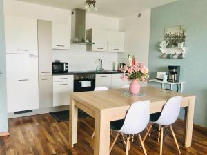 a kitchen with a wooden table and white chairs at NEU! TOP Apartment! 7km Saarbruecken! Terrasse, Garten! in Sulzbach