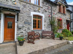a stone house with two benches in front of it at Ty Pili Pala in Betws-y-coed