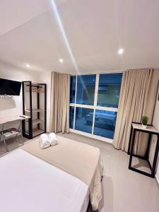 a bedroom with a bed and a desk and a window at Hotel Sol Caribe Cartagena in Cartagena de Indias