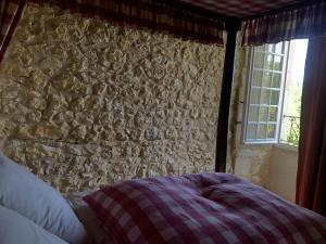 a bedroom with a stone wall with a bed and a window at Château de Monsac in Monsac