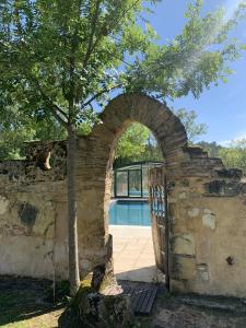 an archway in a stone wall with a pool at Château de Monsac in Monsac