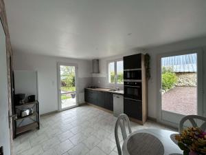 a kitchen with a counter and a table and some windows at Maison proche des plages du DDay in Houesville