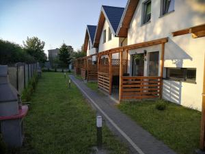a house with a row of wooden stalls next to it at Hibiskus - domki letniskowe in Jastrzębia Góra