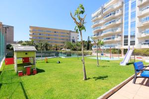 a playground with a play house and a tree at UHC Larimar Family Complex in Salou