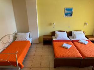 2 letti in una piccola camera con lenzuola arancioni di Michalis Studios & Aparntments a Palaiochóra