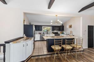 a kitchen with white cabinets and bar stools at Family-friendly cottage with lake access in Chippewa Lake