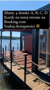 a wooden dock with a house on the water at "C" Domki na wodzie Barczewko 3 z 4 domków in Barczewko