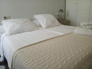 1 cama blanca grande con sábanas y almohadas blancas en Apartamentos MyM, en Jaca