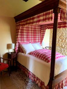 a bedroom with a canopy bed with a red and white curtain at Château de Monsac in Monsac