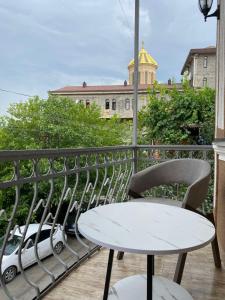 einen Tisch und Stühle auf einem Balkon mit einem Gebäude in der Unterkunft K&N Guesthouse in Tbilisi City