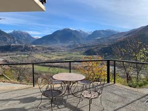 un tavolo e sedie su un balcone con vista sulle montagne di La Roteirolle a Réotier