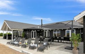 a patio with black chairs and tables and umbrellas at Gorgeous Home In Bogense With Sauna in Bogense +18 photos