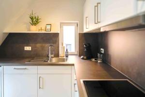 a kitchen with white cabinets and a sink at Lady Milavie apartments in Coburg