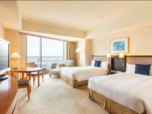um quarto de hotel com duas camas e uma secretária em The Yokohama Bay Hotel Tokyu em Yokohama