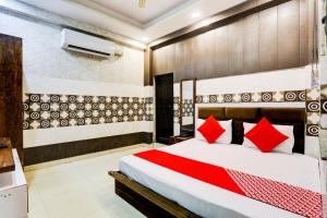 um quarto com uma cama grande e almofadas vermelhas em Flagship Royal Hotel em Kanpur