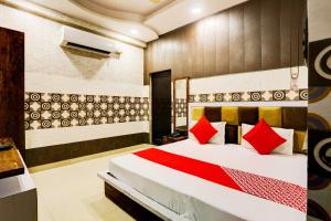 1 dormitorio con 1 cama grande con almohadas rojas en Flagship Royal Hotel en Kānpur