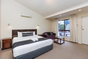 蒂默特Amaroo Motel Tumuts Best Accommodation的一间卧室，里面有一张床、一把椅子和一扇窗户