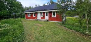 a small red and white house with a yard at Hammarstrandvilla in Hammarstrand