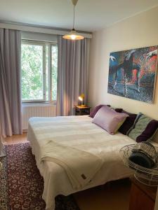 a bedroom with a large bed and a painting on the wall at Retrohenkinen taiteilijakoti - Tampere Kaleva in Tampere