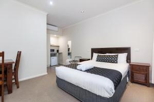 a bedroom with a bed and a desk and a kitchen at Amaroo Motel in Tumut