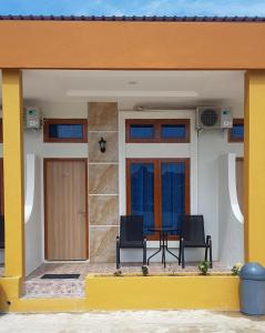 una casa con due sedie e un tavolo sul portico anteriore di Teresra Hotel a Takung-hilir