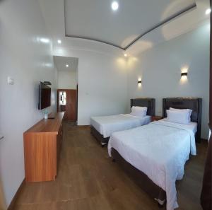 una camera d'albergo con due letti e una televisione di Teresra Hotel a Takung-hilir