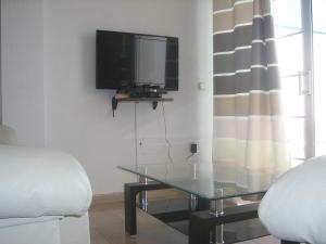 a living room with a tv and a glass table at APT EL FARO ARKADIA BEACH MIJAS COSTA Marvellous Frontbeach with stunning seaviews and historic lighthouse in Mijas Costa