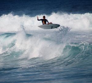 a man riding a wave on a surfboard in the ocean at Casinha do Chico in Charneca