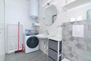 a bathroom with a sink and a washing machine at Memory Box Apartman - Šibenik in Šibenik