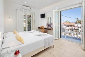 a white bedroom with a bed and a balcony at Bella Vista Beach Hotel in Benitses