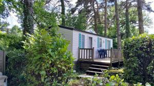 Una pequeña casa blanca con contraventanas azules en un porche. en Camping 46 Rainettes, en Goujounac