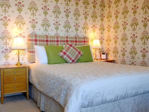 um quarto com uma cama com almofadas verdes e 2 candeeiros em Chough's Nest Hotel em Lynton