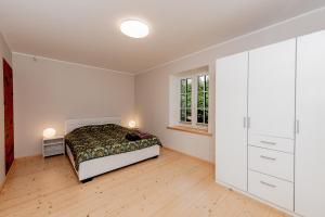 a white bedroom with a bed and a window at Vingi Familyhouse with free parking and sauna in Pärnu