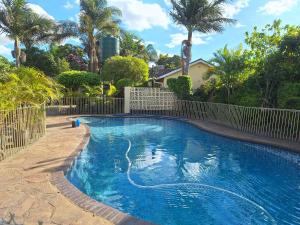 a swimming pool with a fence and palm trees at Beautiful 2-Bedroomed Guest Cottage in Harare in Harare
