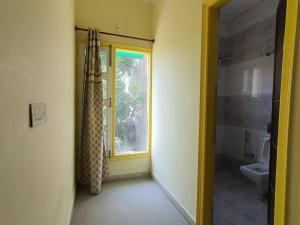 a bathroom with a toilet and a window with a shower at Comfy 3BHK house with Cinema like Home Theatre ! in Sohāna +23 photos