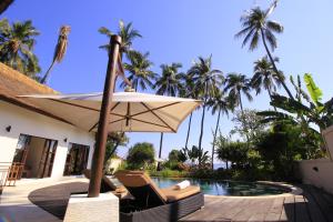 an umbrella and chairs next to a swimming pool at Kembali Villa in Kubutambahan