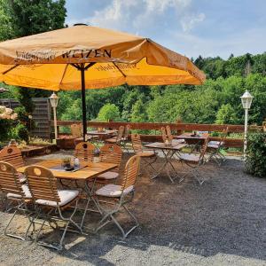 a patio with tables and chairs under an umbrella at Brauner Hirsch in Hannoversch Münden