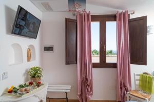 a room with a table and a window with pink curtains at Il Marchese Hotel & Spa in Sciacca