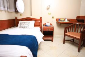 a bedroom with a bed and a chair and a desk at Paris Hotel in Nairobi