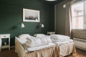 a bedroom with green walls and a bed with white pillows at Perssons i Backens Pensionat- Sjötorps Vandrarhem & Rum in Sjötorp