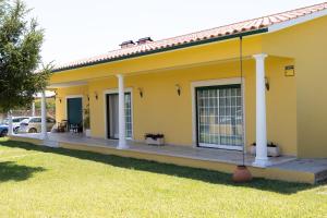 a yellow house with a porch and a yard at Casa da Ereira in Montemor-o-Velho