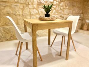 a wooden table with two white chairs and a plant at MCC St Rita in Il-Furjana