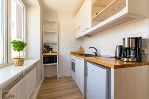 a kitchen with white cabinets and a counter top at Parkside Central Apartment by Kuus Sõlme in Kuressaare +4 photos