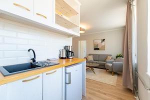 a kitchen with a sink and a couch in a living room at Parkside Central Apartment by Kuus Sõlme in Kuressaare