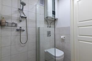 a white bathroom with a shower and a toilet at Parkside Central Apartment by Kuus Sõlme in Kuressaare